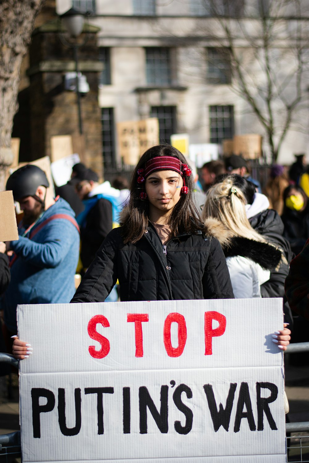 a woman holding a sign that says stop puttin's war