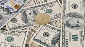 a pile of money with a bitcoin sitting on top of it