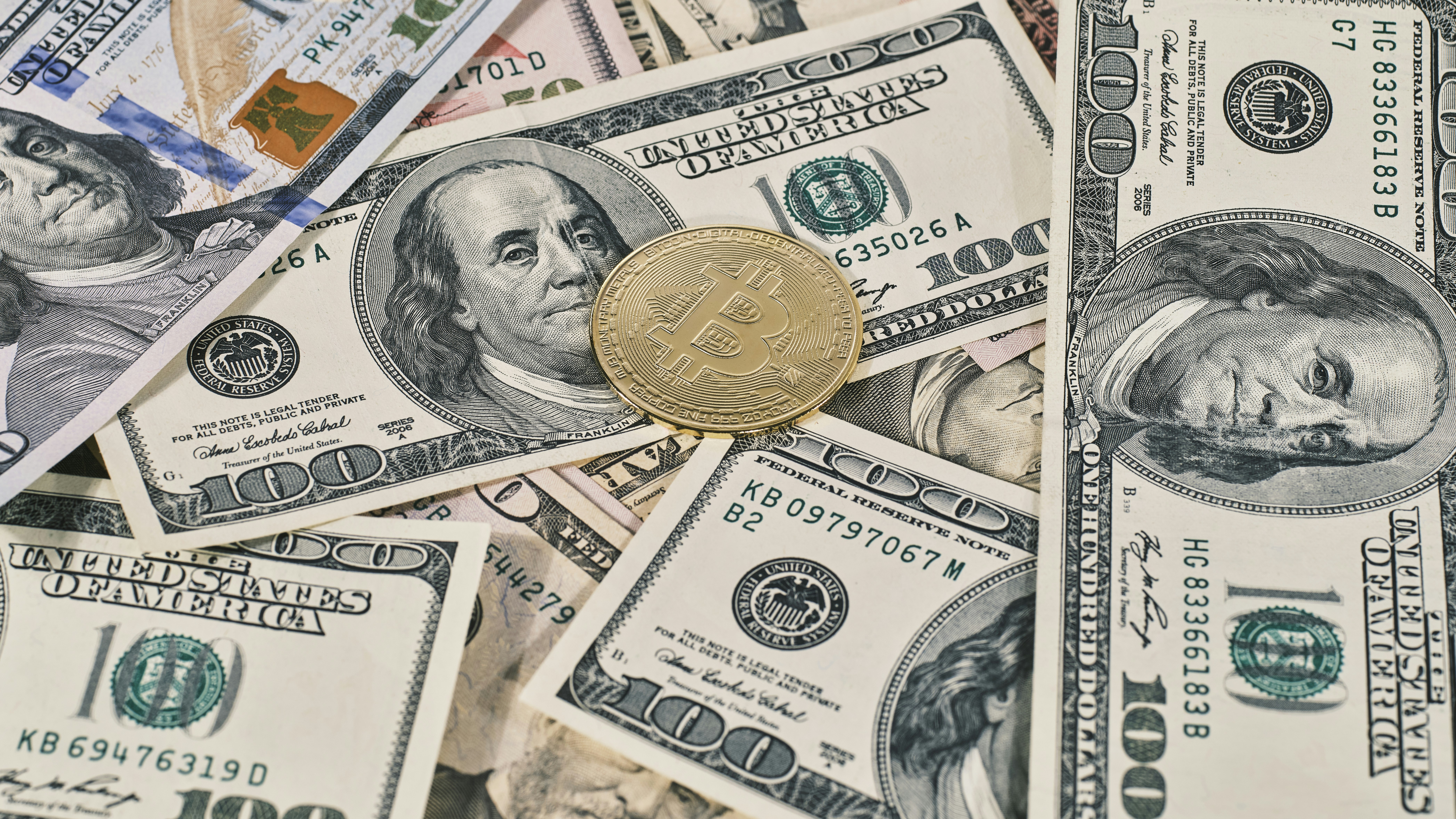 Golden symbolic coin Bitcoin on banknotes of one hundred dollars