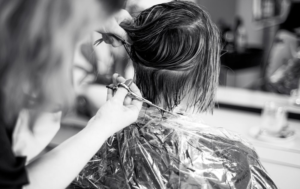 a woman cutting another woman's hair in a salon