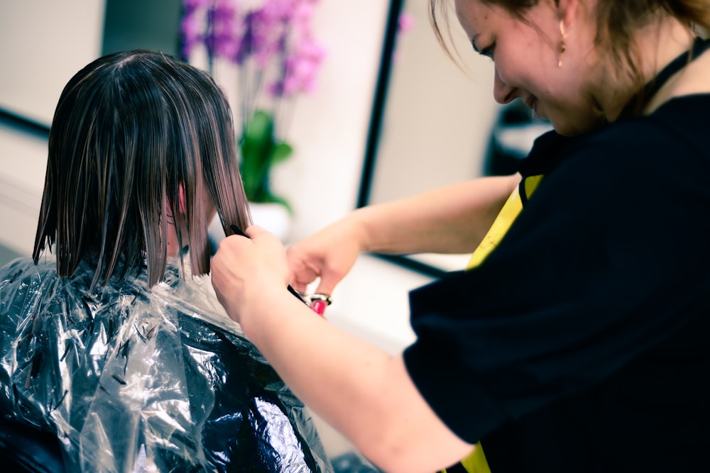 a woman cutting another woman's hair in a salon