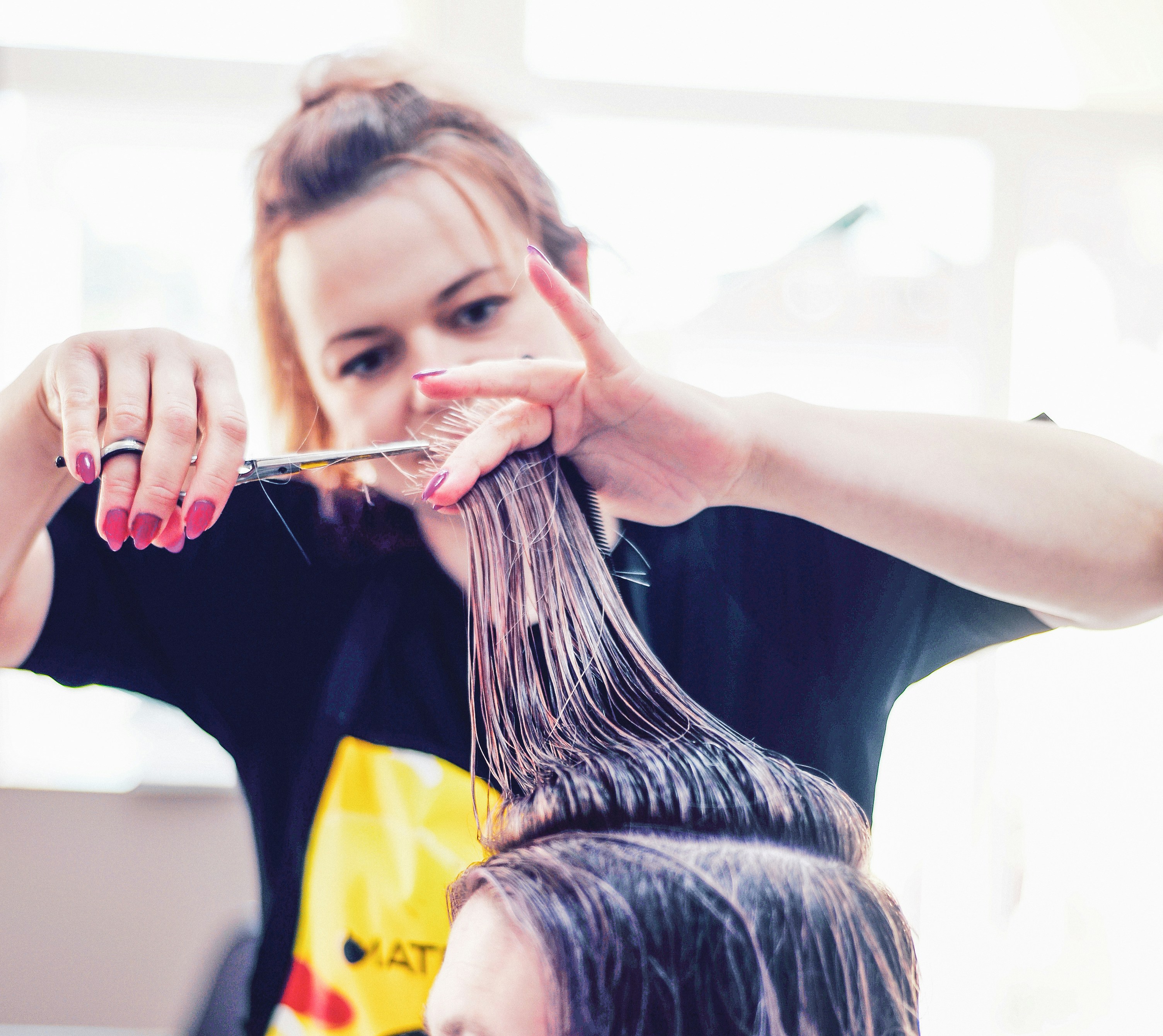a woman cutting another woman's hair with scissors
