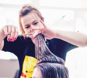 a woman cutting another woman's hair with scissors