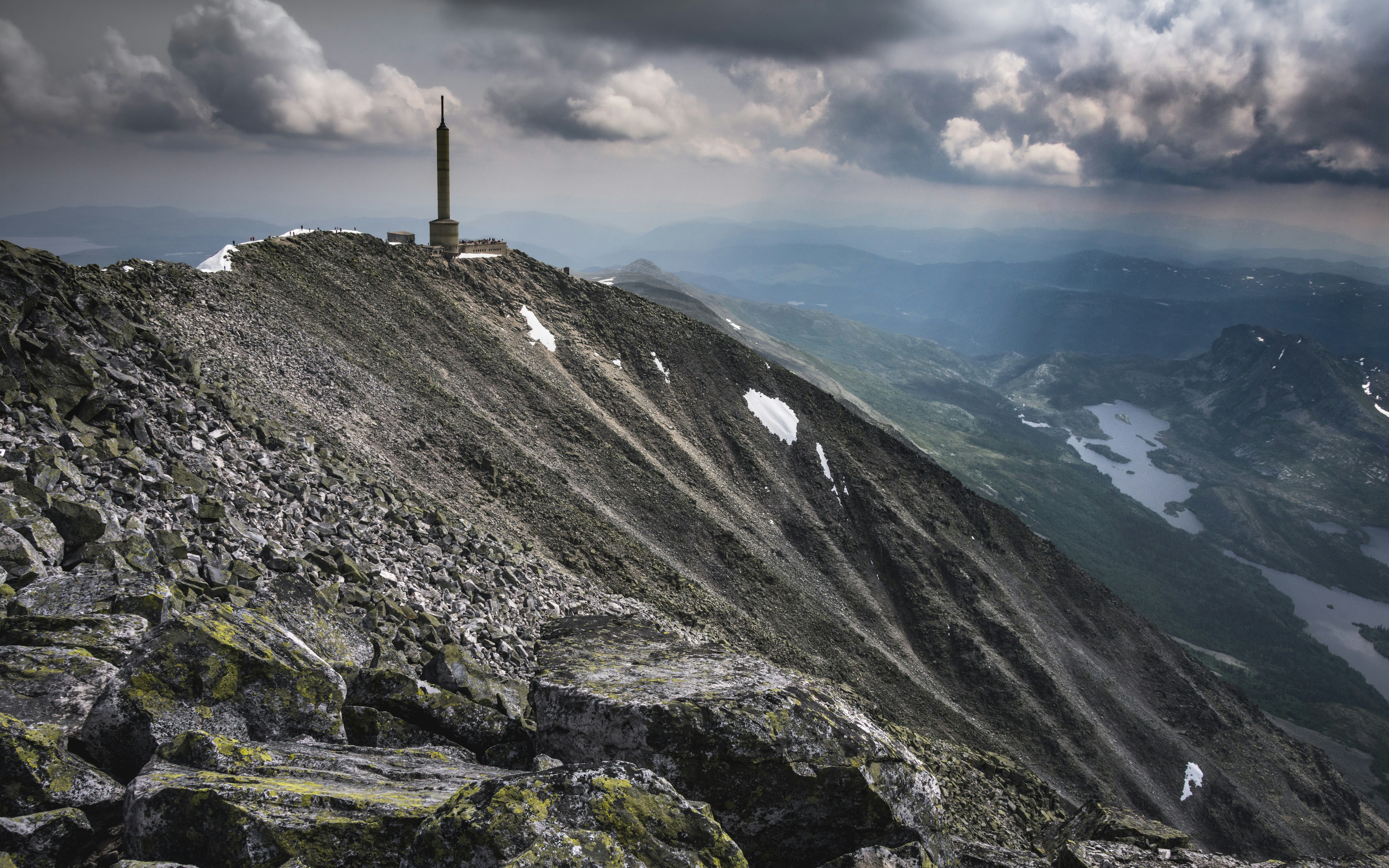 a tall tower on top of a mountain under a cloudy sky