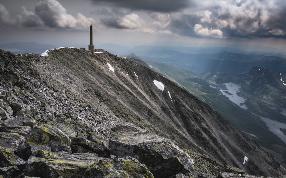 a tall tower on top of a mountain under a cloudy sky
