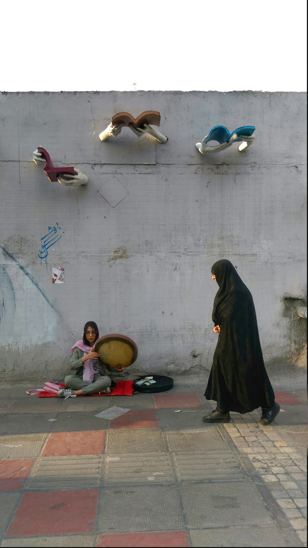 a woman and child sitting on the ground in front of a wall