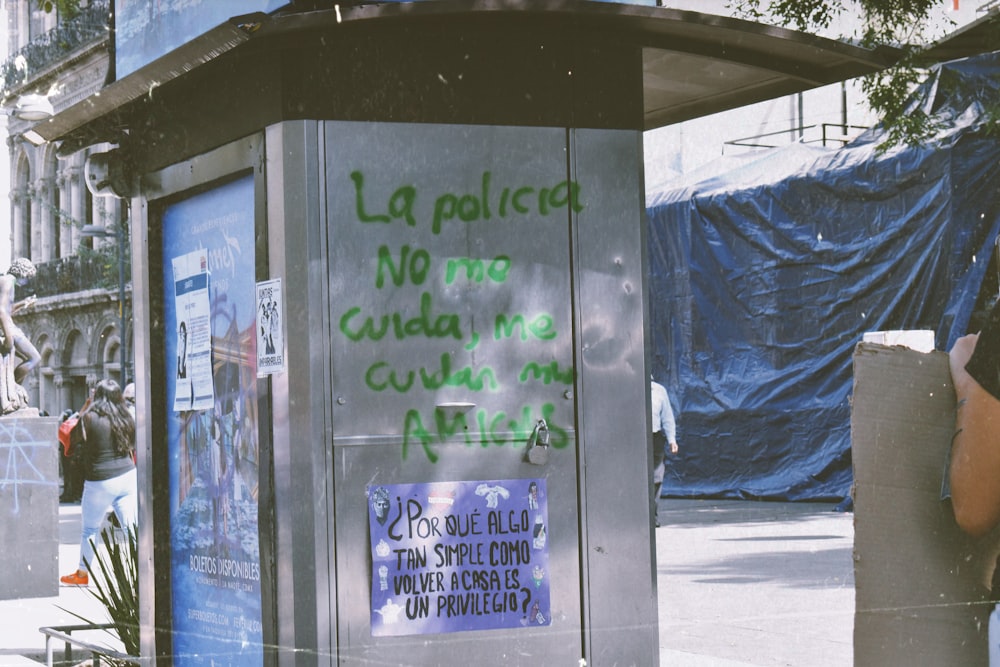 a man standing next to a bus stop covered in graffiti