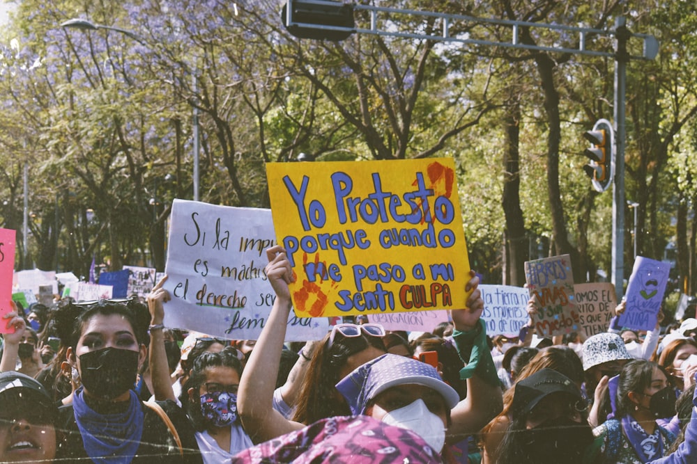 a crowd of people holding signs and wearing masks