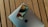 A smartphone rests on top of a closed laptop, both placed on a wooden surface. The phone's screen displays the time and date with a colorful background. The laptop's exterior features a prominent logo.
