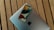 A smartphone rests on top of a closed laptop, both placed on a wooden surface. The phone's screen displays the time and date with a colorful background. The laptop's exterior features a prominent logo.