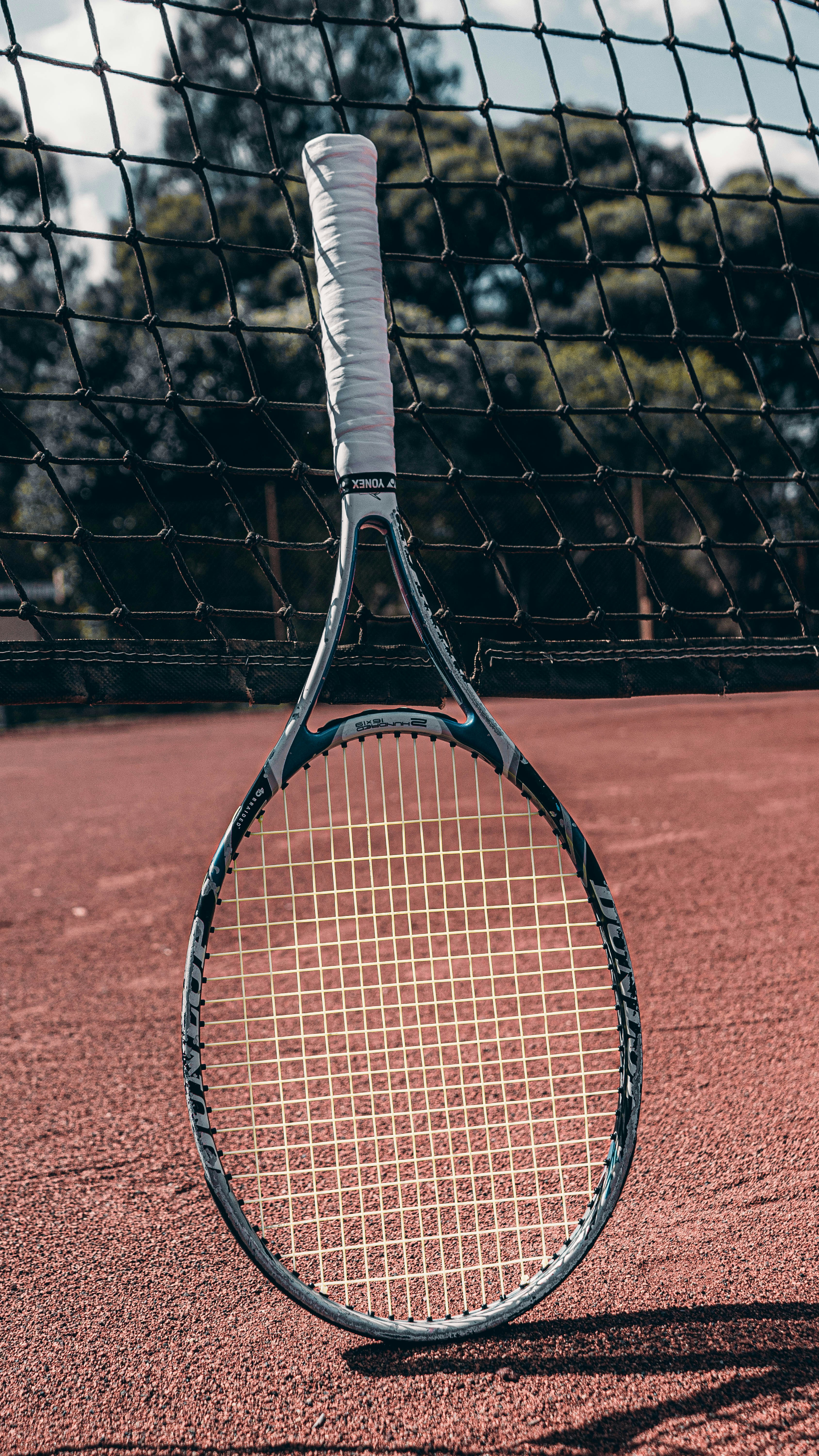 a tennis racket on a tennis court with a net in the background