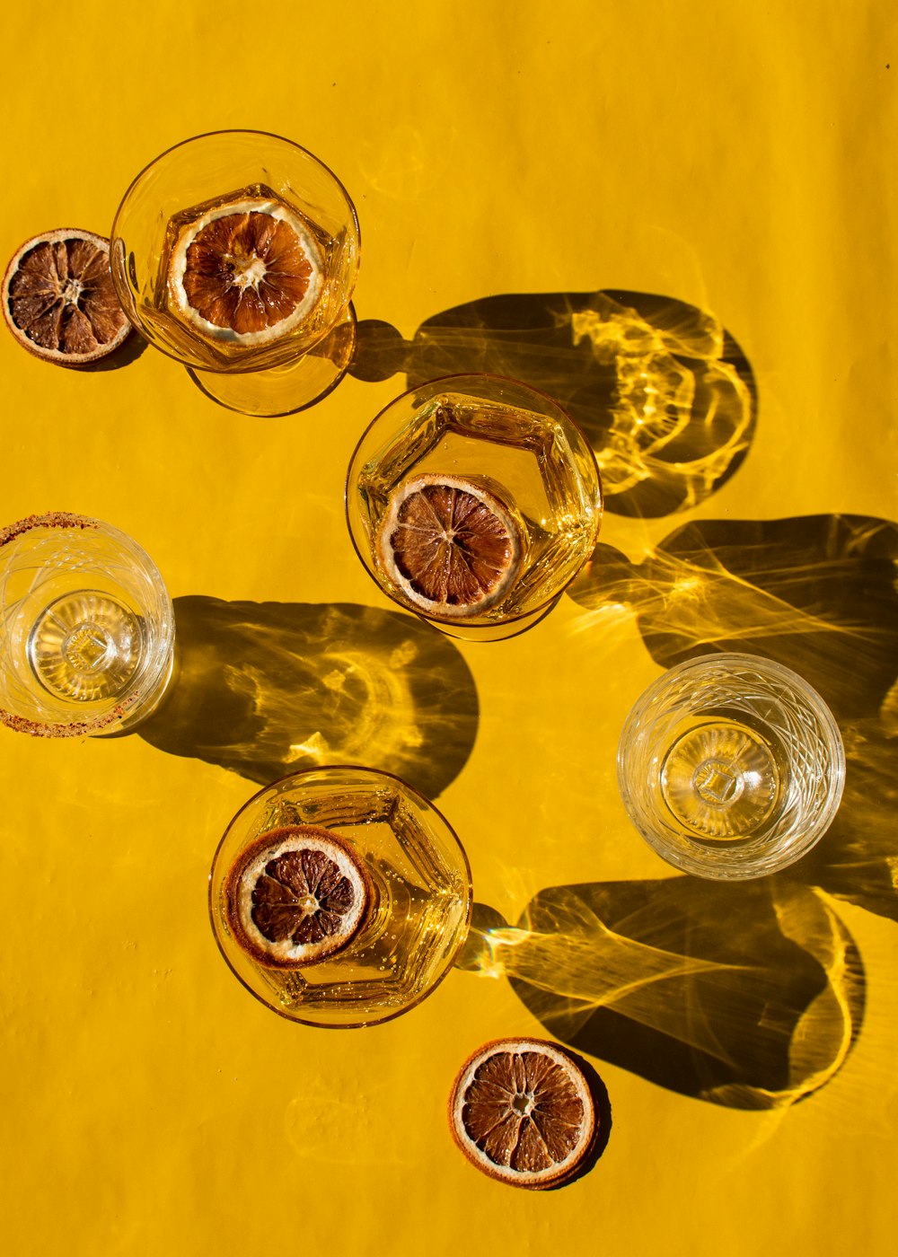 three glasses of wine with orange slices on a yellow background