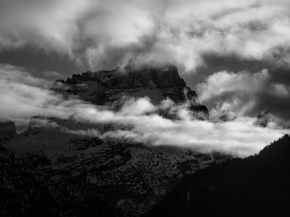 a black and white photo of a mountain covered in clouds