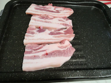Artisan curing process showing seasoned pork belly resting in a copper curing tray.