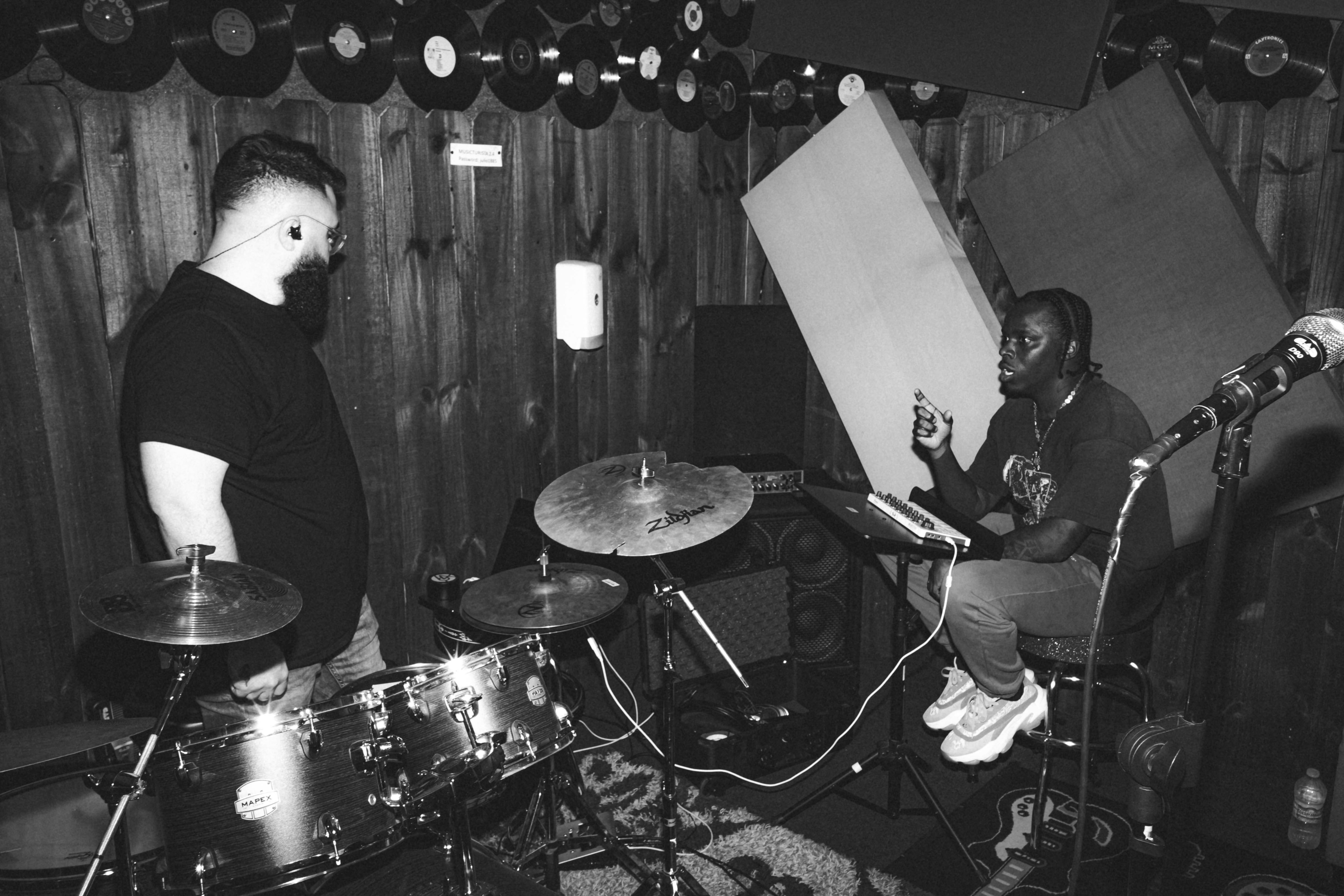 रिहर्सल स्टूडियो में ड्रम बजाते दो संगीतकार