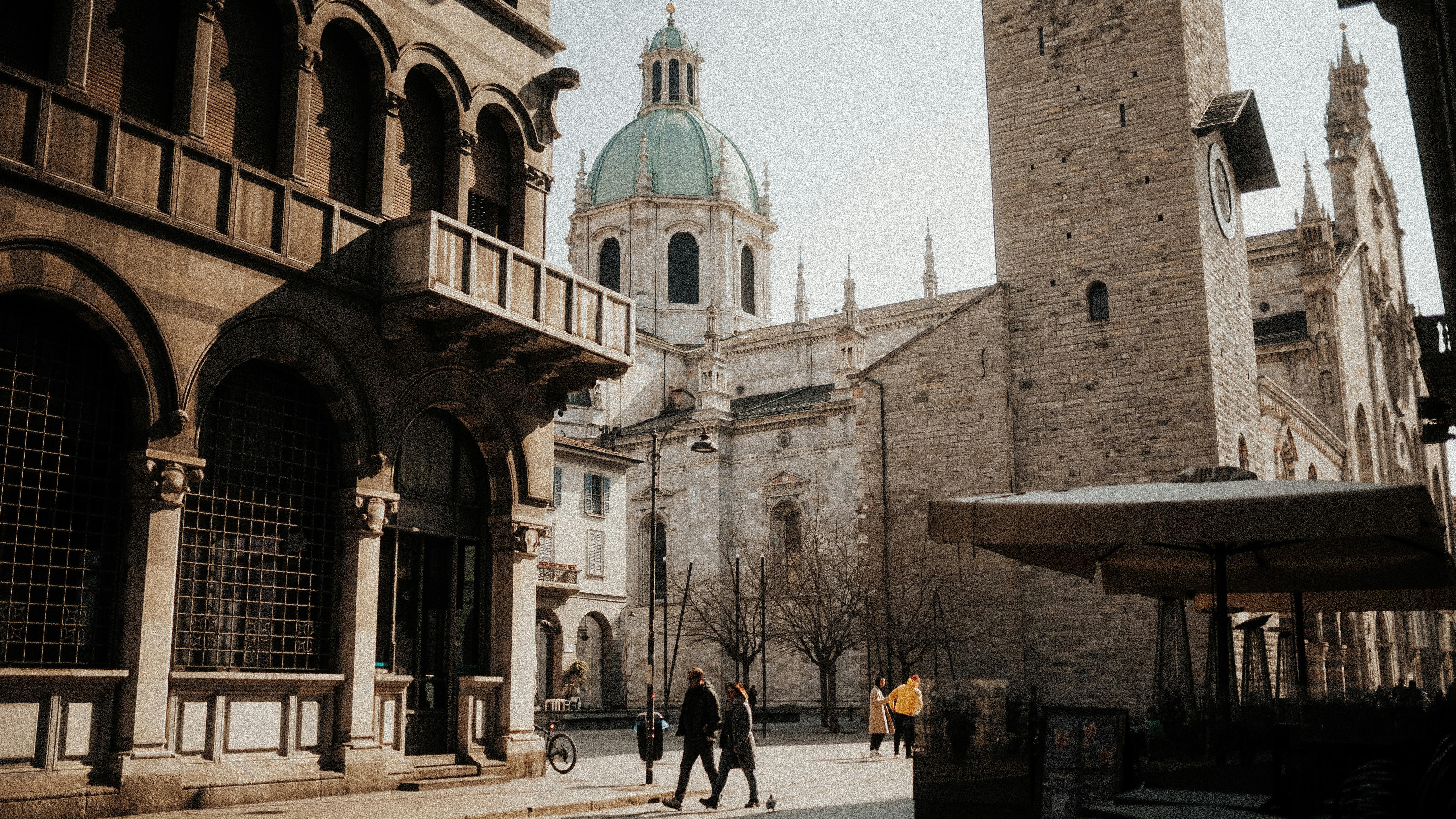 a couple of people walking down a street next to tall buildings