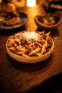 A vibrant plate of loaded fries topped with cheese and jalapeños, styled on a dark background.
