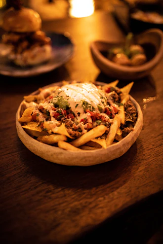 A colorful bowl of spicy loaded fries topped with melted cheese and jalapeños.
