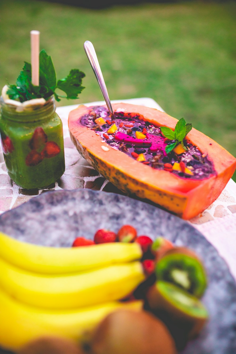 a plate of fruit and a jar of green smoothie