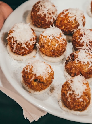 a person holding a plate of food with powdered sugar on it