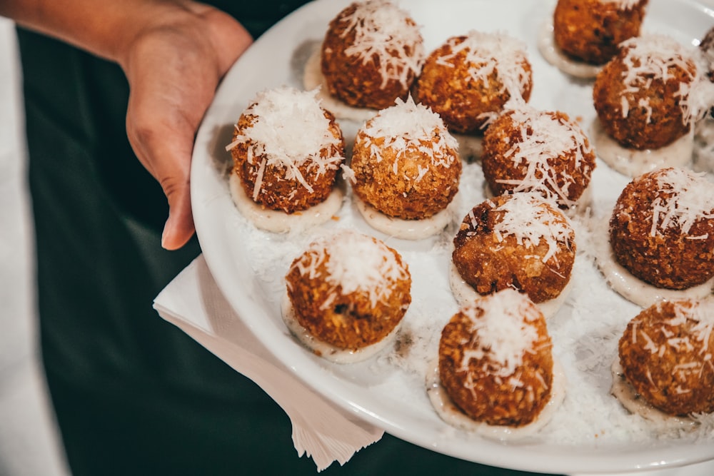 a person holding a plate of food with powdered sugar on it