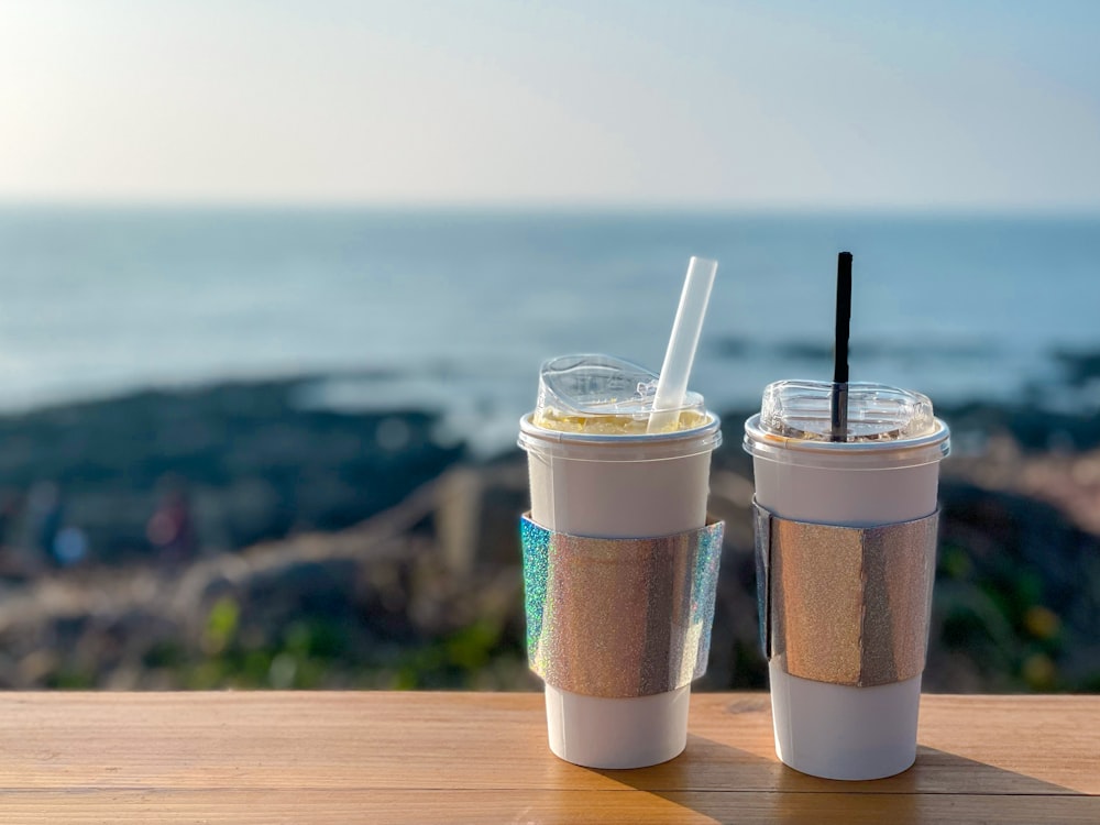 two cups of coffee on a table with a view of the ocean