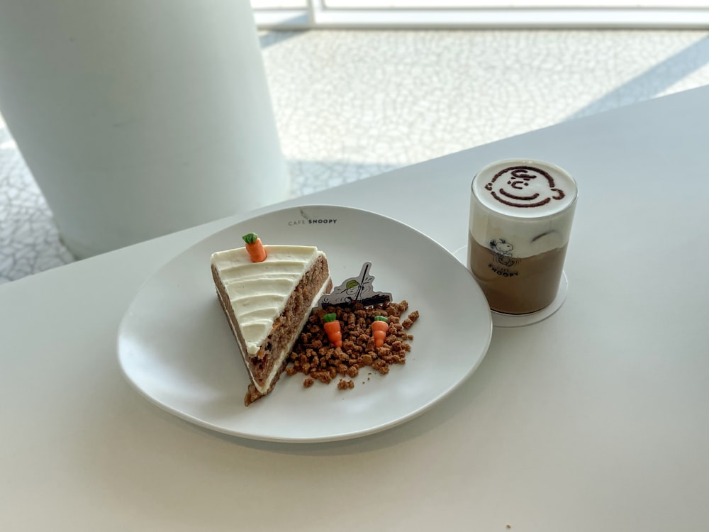 a white plate topped with a slice of cake next to a cup of coffee