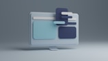 A 3D illustration of a computer monitor with abstract shapes and rectangles layered over the screen, featuring a minimalist design with a cool color palette.
