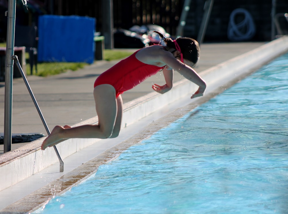 a woman in a red swimsuit diving into a pool