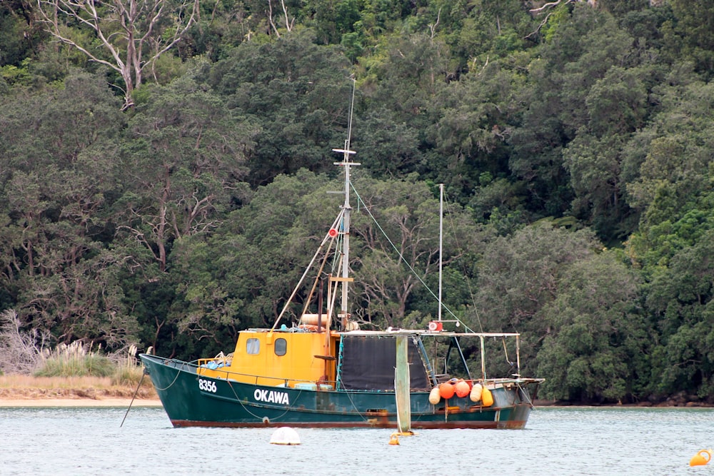 a yellow and green boat floating on top of a body of water