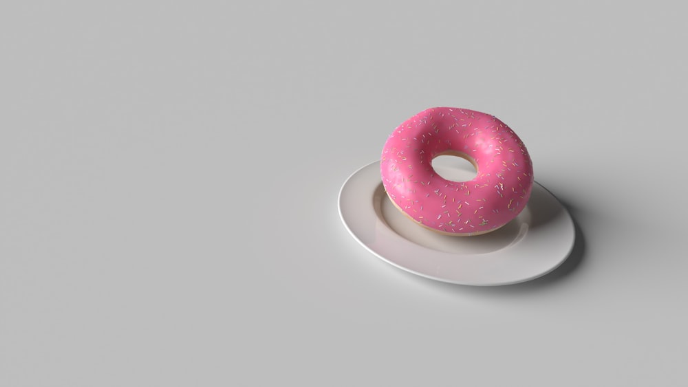a pink donut sitting on top of a white plate