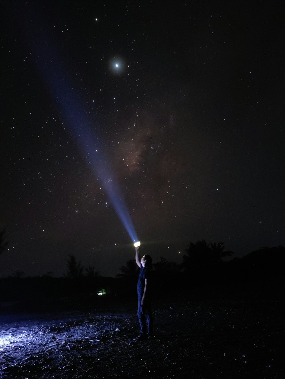 a man holding a flashlight up to the sky