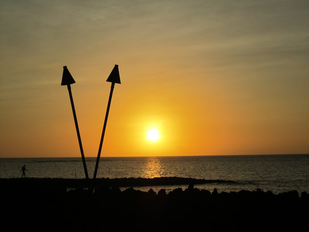 um par de postes sentados no topo de uma praia ao lado do oceano