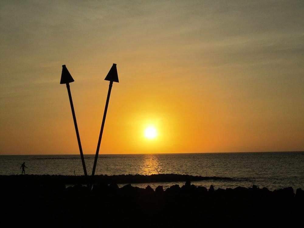 a couple of poles sitting on top of a beach next to the ocean