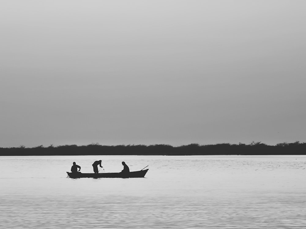 three people in a small boat on a large body of water