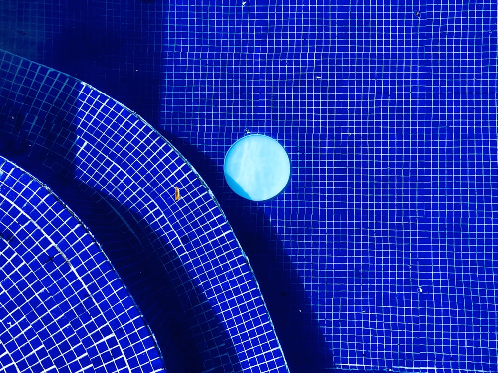 a blue tiled swimming pool with a blue frisbee