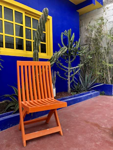 a wooden chair sitting in front of a blue building