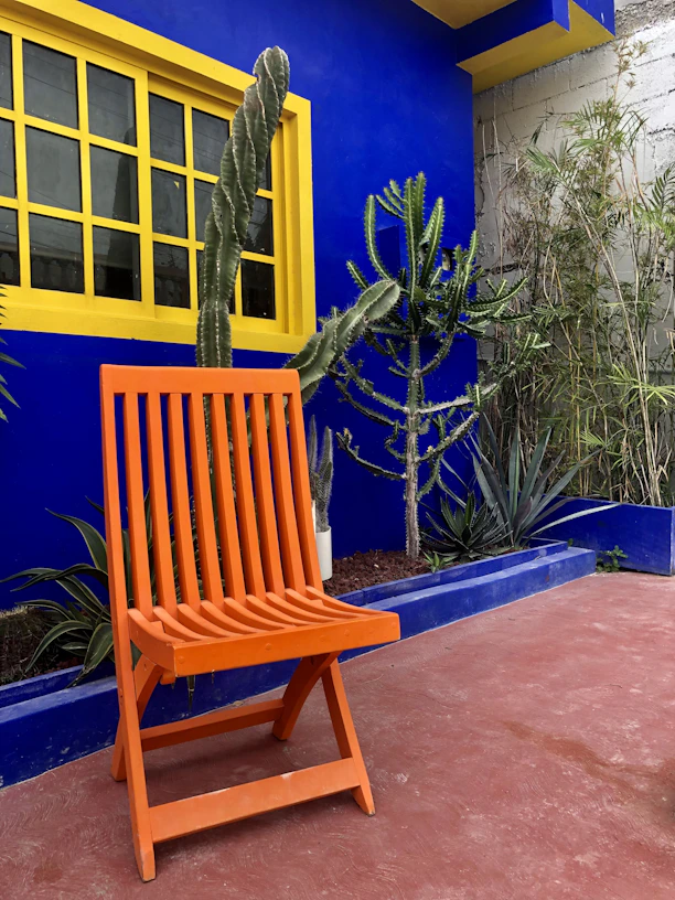 a wooden chair sitting in front of a blue building