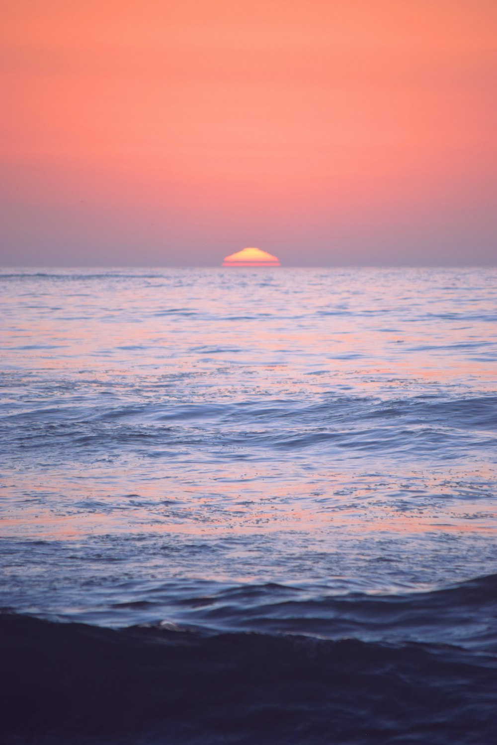 the sun is setting over the ocean with waves