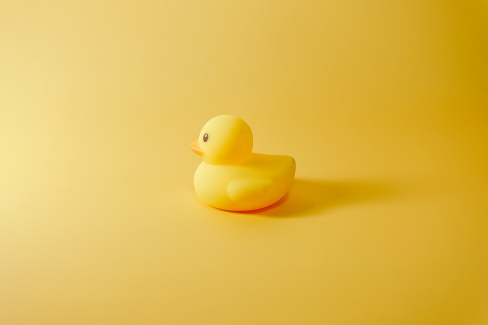 un canard en caoutchouc jaune assis sur une surface jaune