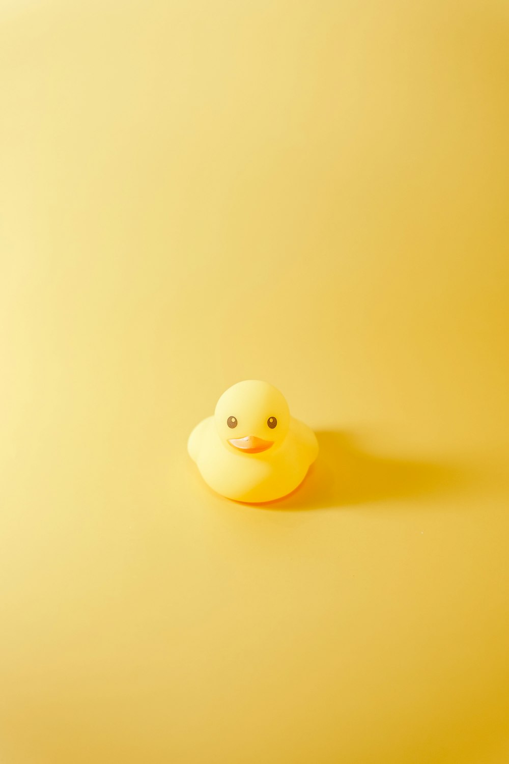 a rubber duck sitting on top of a yellow surface