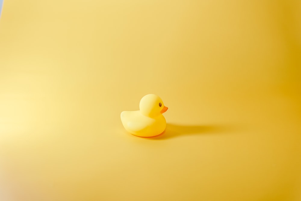 a rubber ducky sitting on a yellow surface