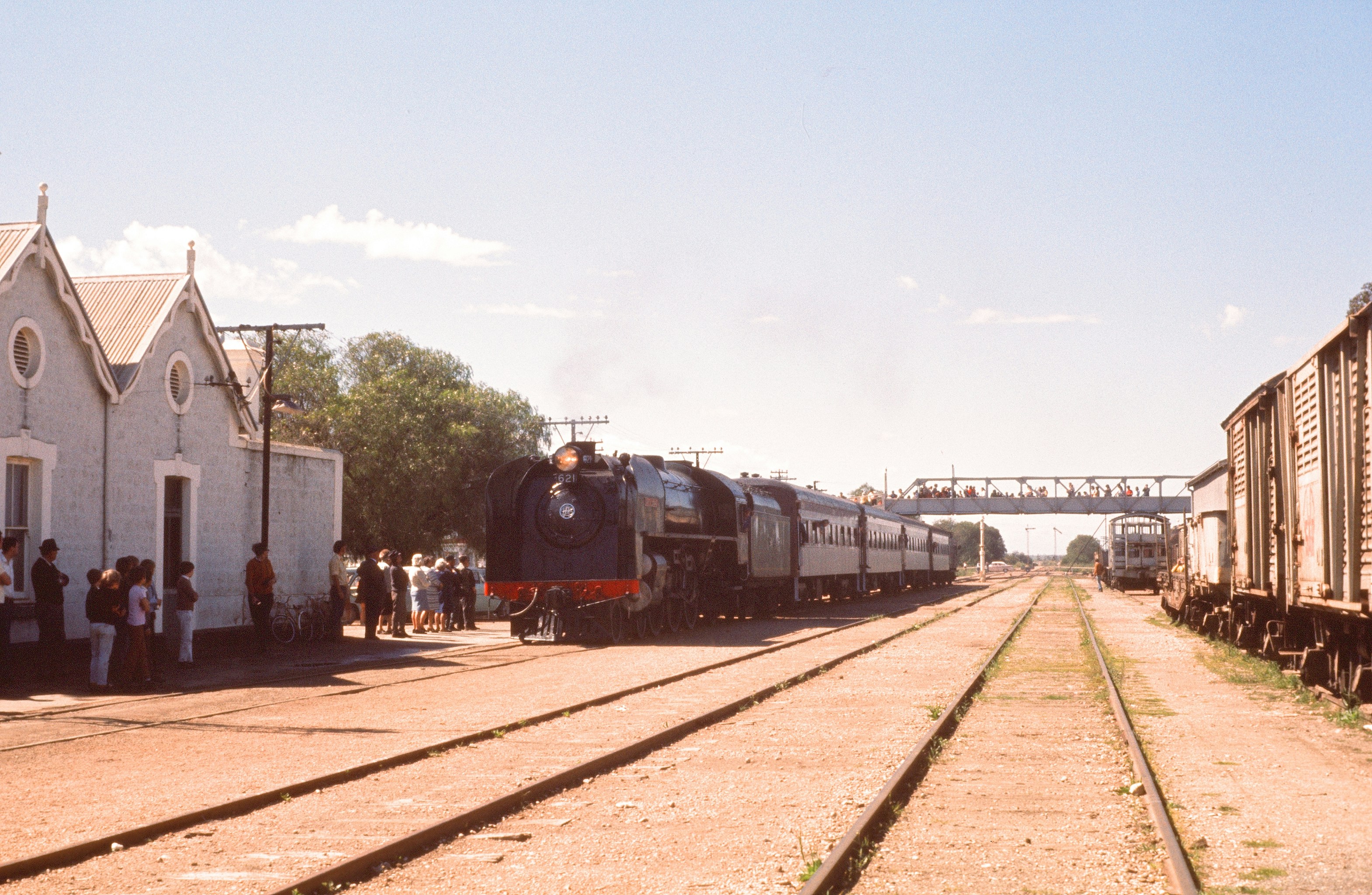 a train traveling down train tracks next to a white building