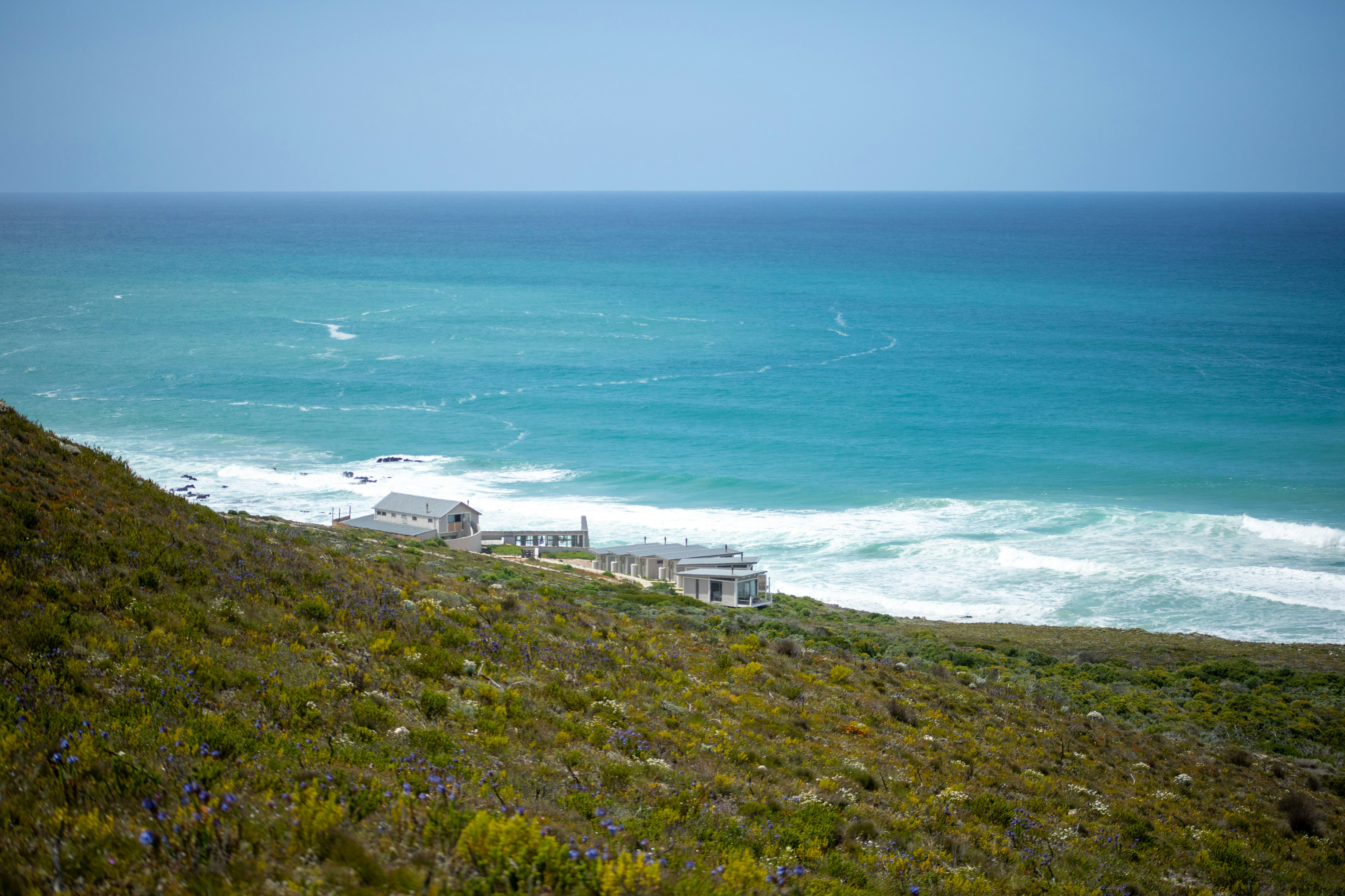 a house sitting on top of a lush green hillside next to the ocean
