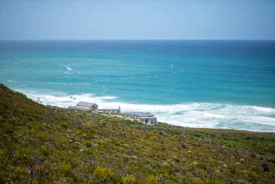 a house sitting on top of a lush green hillside next to the ocean