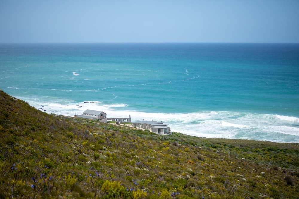 a house sitting on top of a lush green hillside next to the ocean