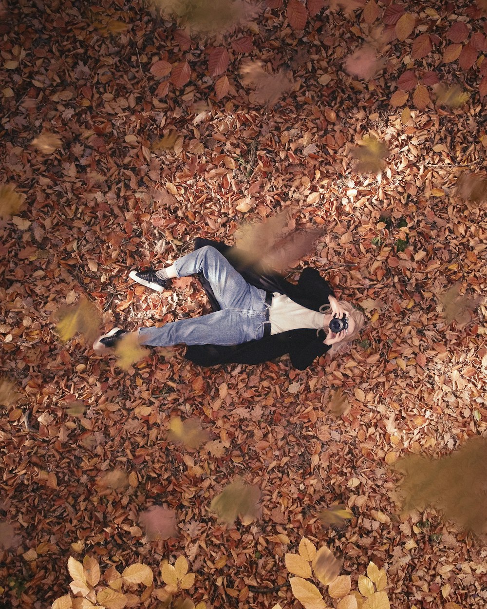 a man laying on the ground surrounded by leaves