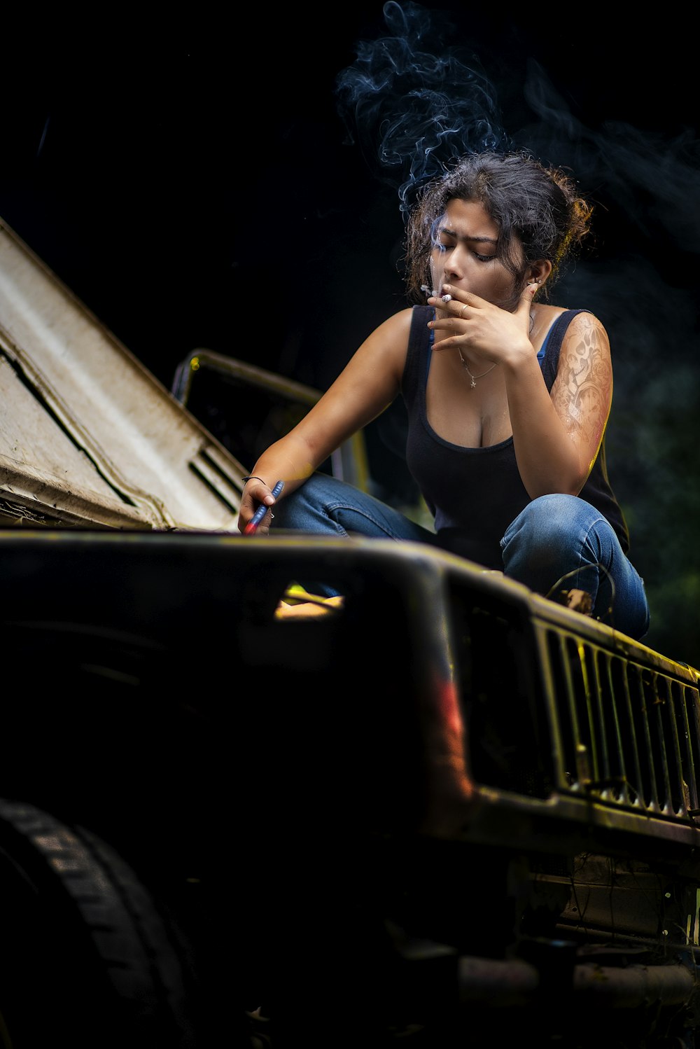 a woman smoking a cigarette sitting on the back of a truck