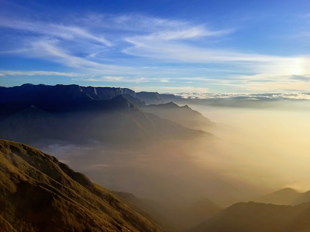 a view of a mountain range with the sun shining through the clouds