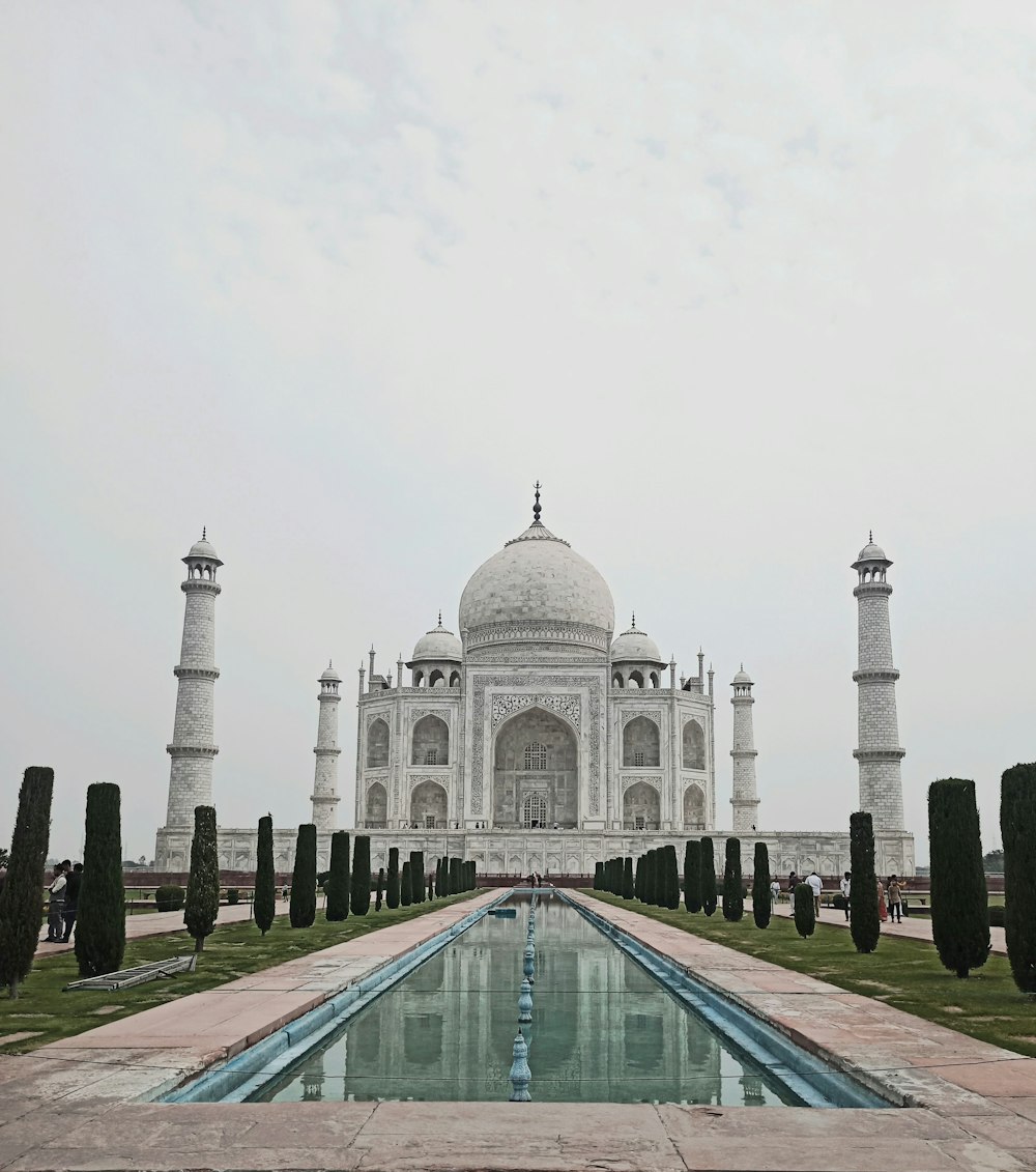 a large white building with a long pool in front of it